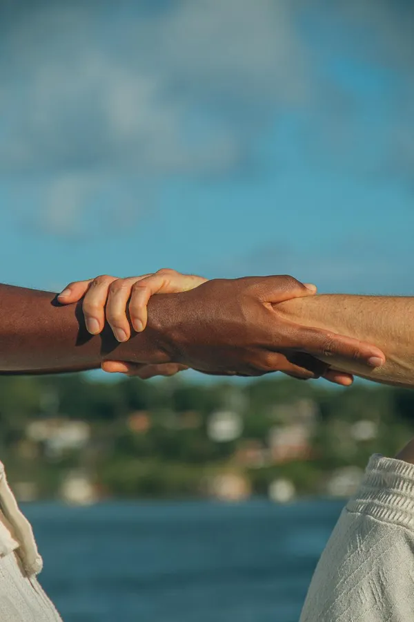 Mains entrelacées devant la mer - Brasil Sunshine, lien entre cultures